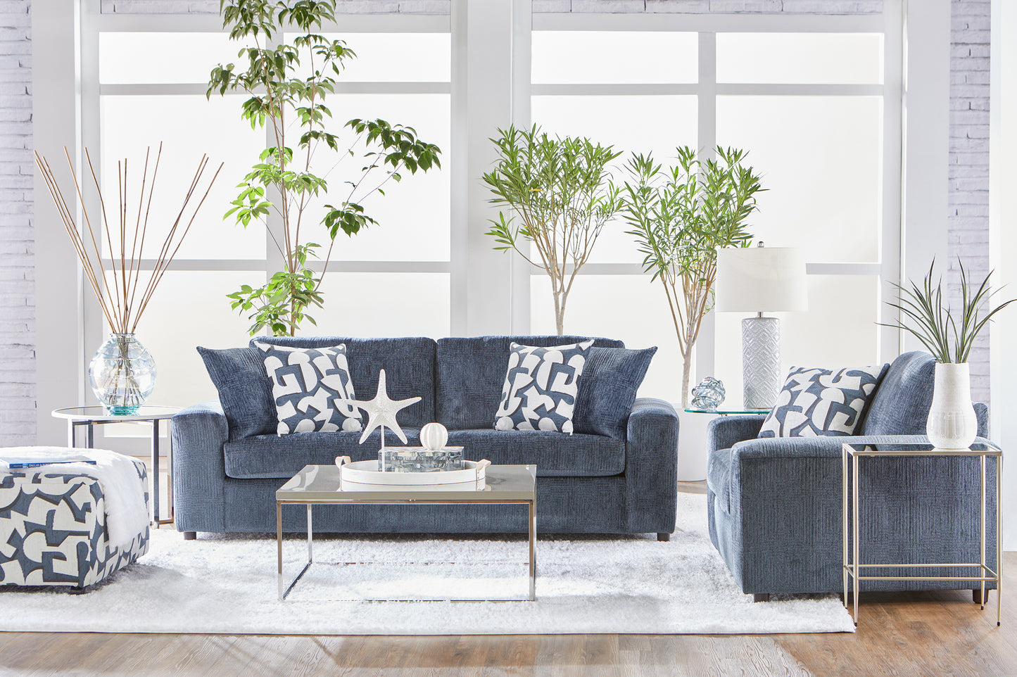 Dark navy blue sofa and loveseat set with geometric accent pillows in a bright modern living room