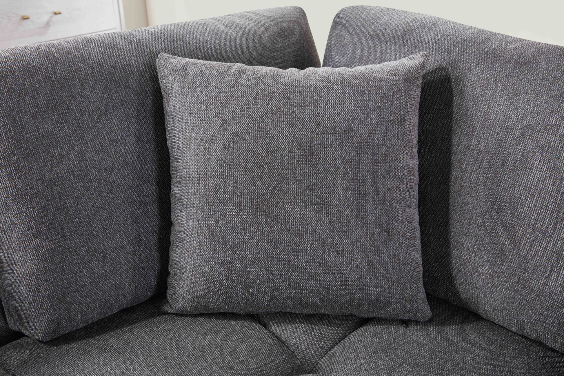 Grey L-shaped sectional sofa with vertical channeling and bolster cushions in a modern living room