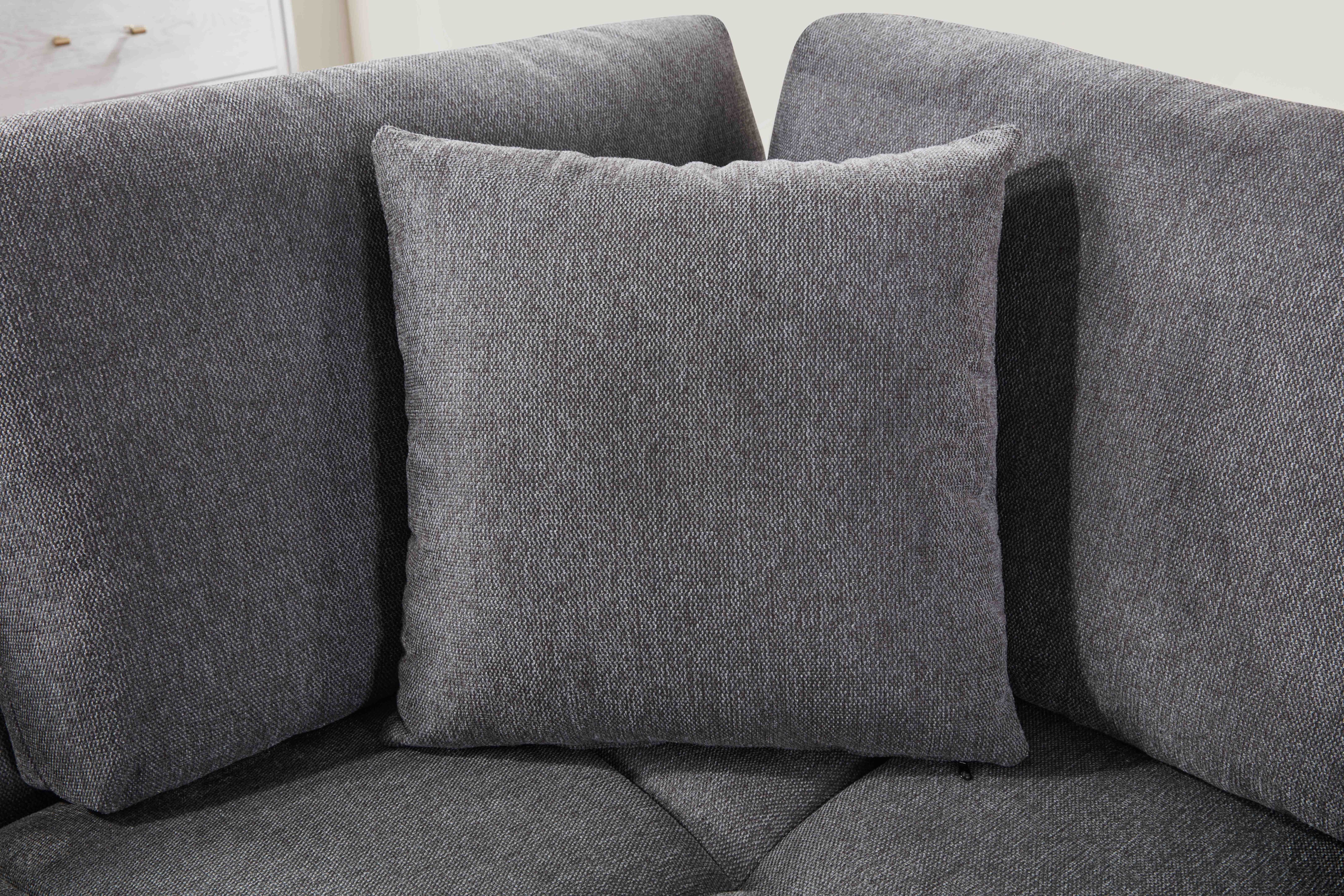 Grey L-shaped sectional sofa with vertical channeling and bolster cushions in a modern living room