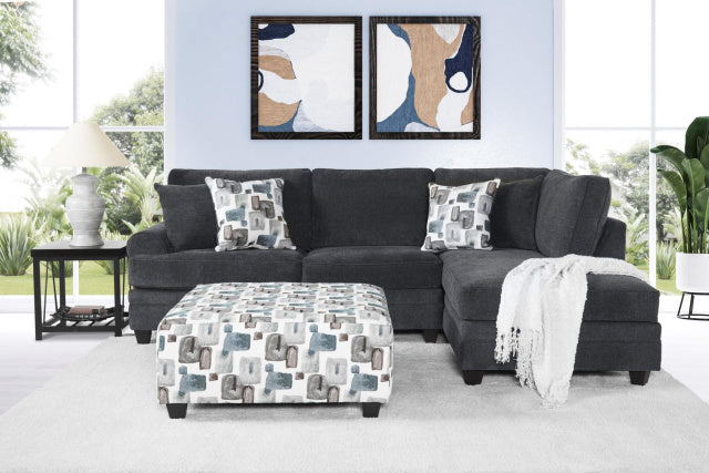 Gray sectional sofa with patterned cushions and ottoman in a living room setting.