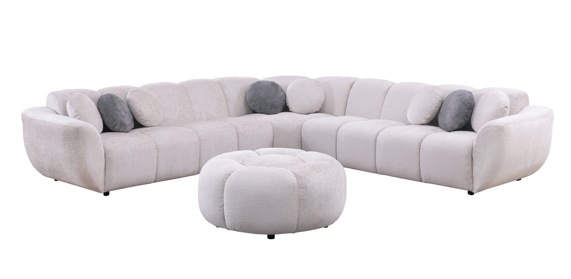 Beige fabric channel-tufted sectional sofa with round ottoman and accent pillows in a modern living room
