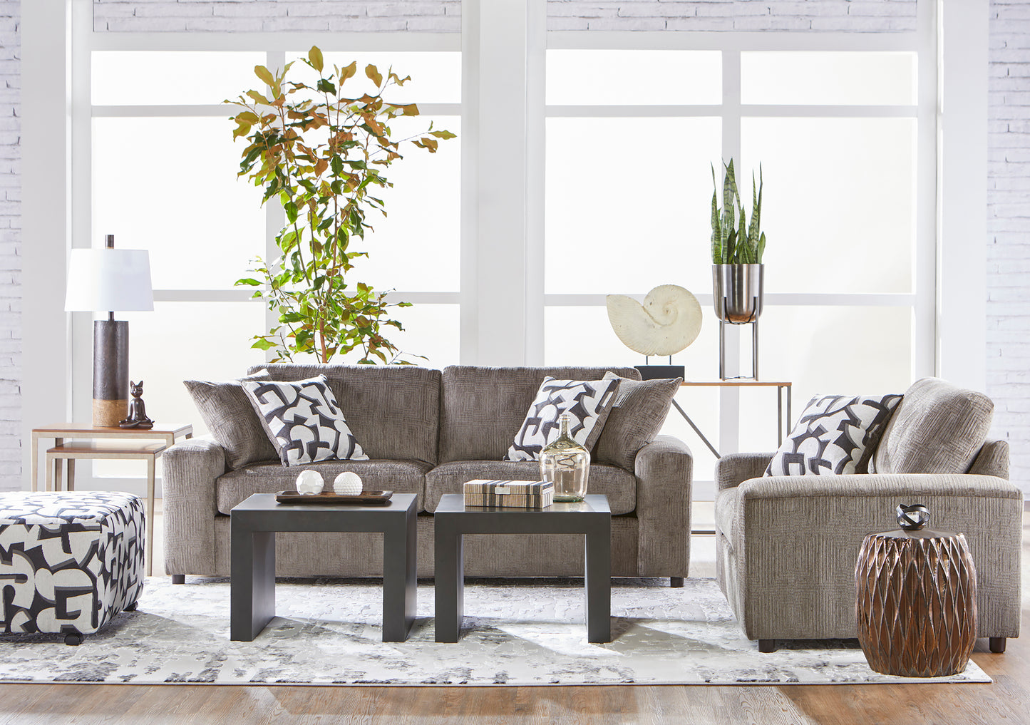 Modern brown fabric sofa and loveseat living room set with patterned accent pillows and contemporary décor.”