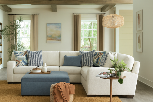 Cozy living room with a cream sectional sofa, blue ottoman, and decorative pillows.