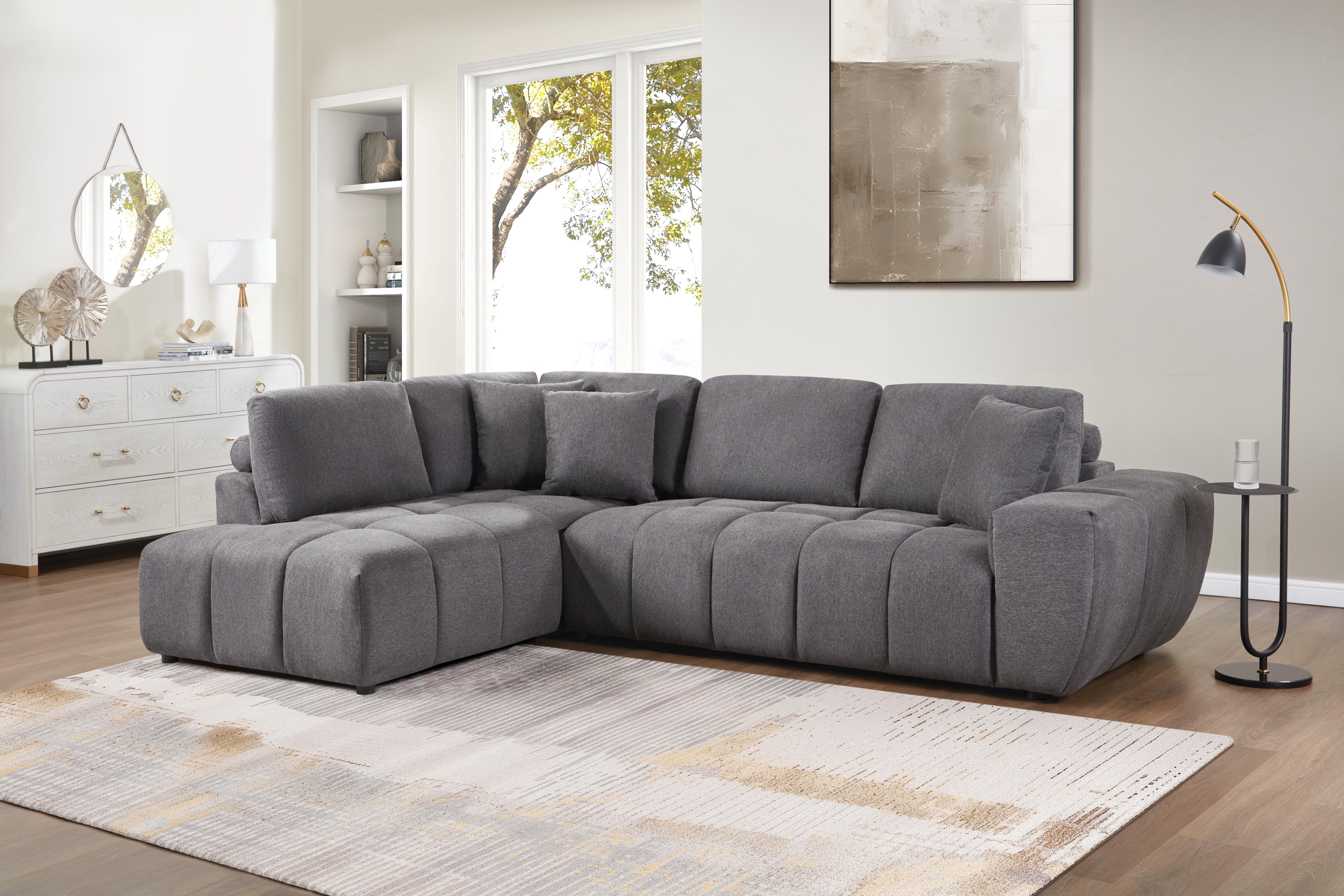 Grey L-shaped sectional sofa with vertical channeling and bolster cushions in a modern living room