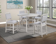 Dining room set with a round table and four chairs in a well-lit room.