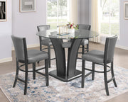 Dining room with a glass table and four chairs on a patterned rug.