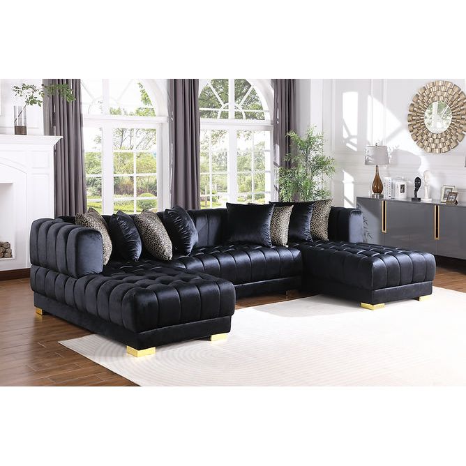 Black velvet sectional sofa with gold legs and accent pillows in a living room