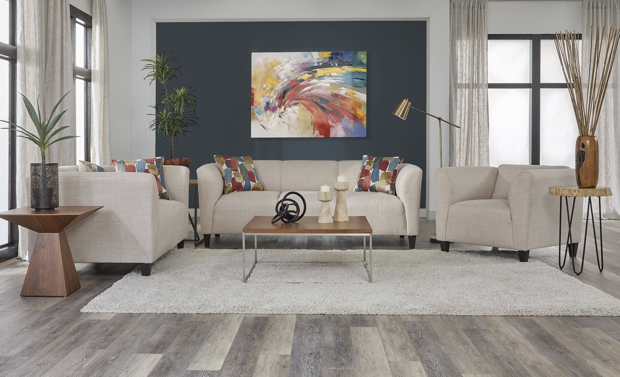 Modern cream fabric sofa and loveseat set with curved arms and colorful geometric accent pillows.”