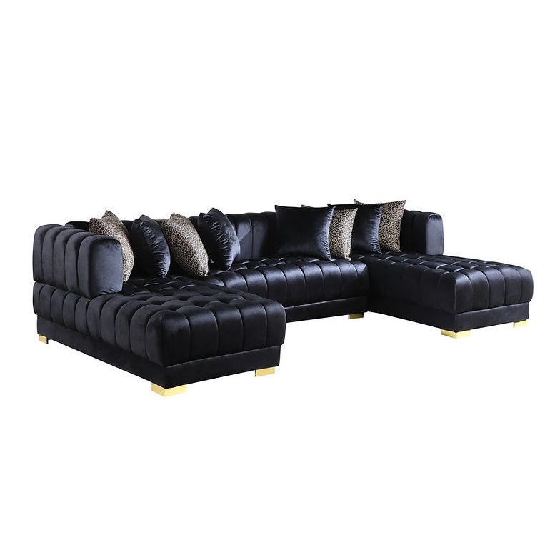 Black velvet sectional sofa with gold legs and accent pillows in a living room