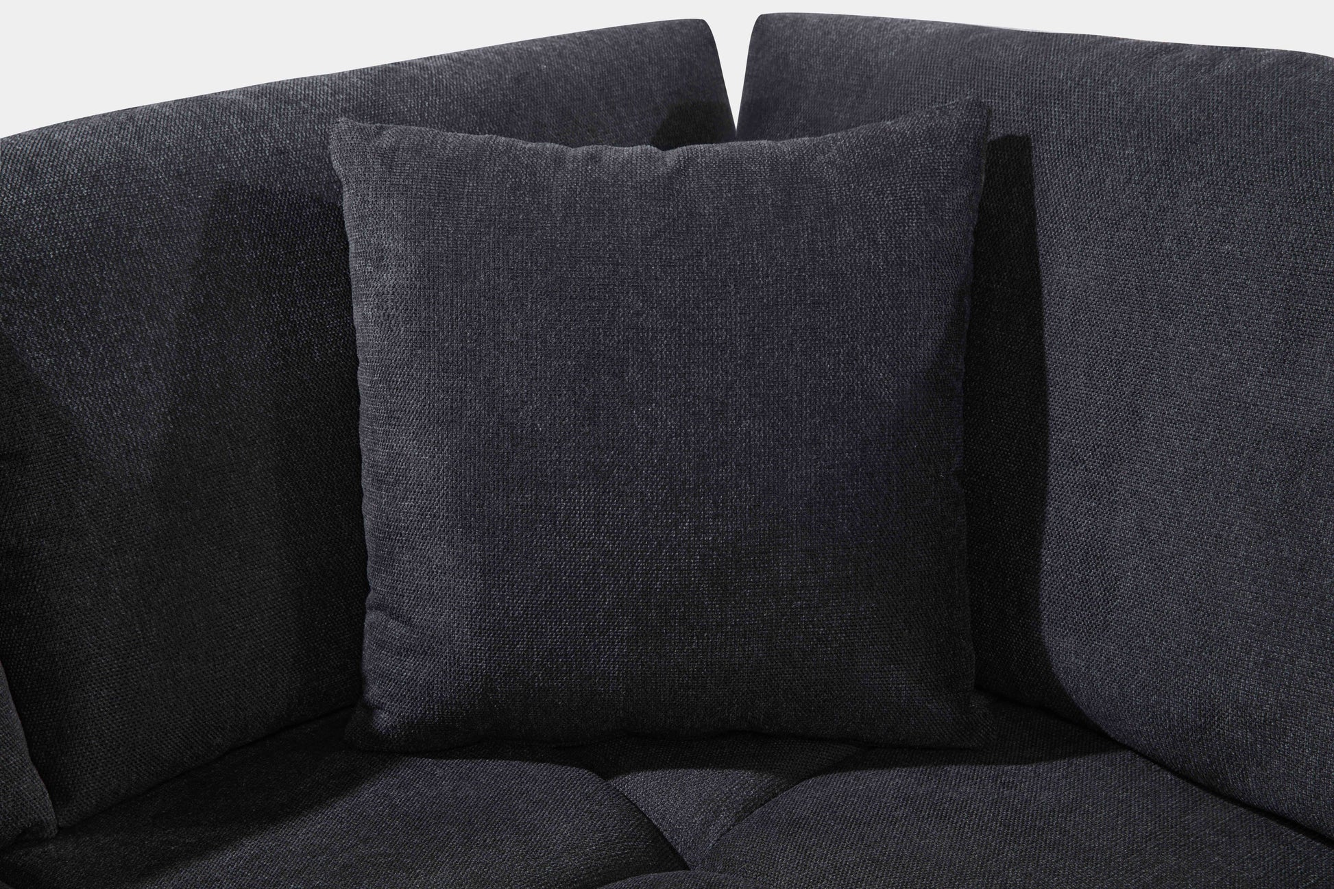 Black low-profile L-shaped sectional sofa with vertical channel tufting in a modern living room